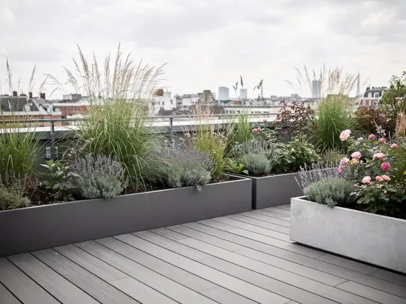 Weelderige rooftop stadstuin met siergras, lavendel en struikrozen in betonnen bakken op een modern penthouse.